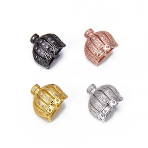 May include: Four decorative bead charms in black, rose gold, gold, and silver. Each charm has a bell-like shape with a textured surface and is encrusted with small, sparkling stones. The charms are displayed on a white background.
