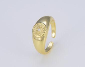 Puede incluir: Anillo ajustable de oro con un diseño circular que presenta una pequeña piedra preciosa transparente en el centro. El anillo tiene un patrón texturizado en forma de ojo alrededor de la piedra preciosa.