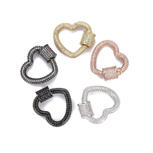 Puede incluir: Cuatro cierres en forma de corazón con un barril decorativo en el centro. Los cierres están hechos de metal y están adornados con diamantes de imitación transparentes. Los cierres están disponibles en oro, plata, negro y oro rosa.