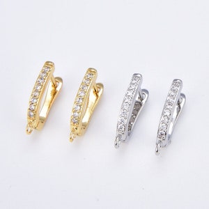 May include: Two pairs of hoop earrings with a row of clear cubic zirconia stones. One pair is gold-toned and the other is silver-toned.