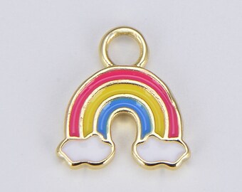Könnte beinhalten: Ein goldfarbener Regenbogen-Anhänger mit einem rosa, gelben und blauen Bogen. Der Regenbogen hat weiße Wolken am unteren Rand. Der Anhänger hat oben eine Schlaufe zum Befestigen an Schmuck oder anderen Bastelarbeiten.