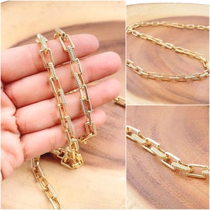 May include: Gold chain necklace with square links, each link is encrusted with small clear stones.