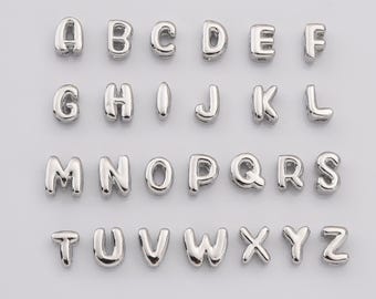 May include: Silver alphabet letter beads, A through Z, for jewelry making.