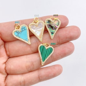 May include: Four gold heart-shaped pendants with different colored stones. The pendants are numbered #01, #02, #03, and #04.  #01 has a turquoise stone, #02 has a white stone, #03 has a green and brown stone, and #04 has a green stone.