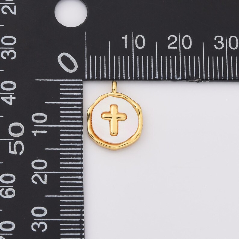 May include: Gold-toned pendant charm with a white enamel cross design. The pendant is approximately 1 cm in diameter.