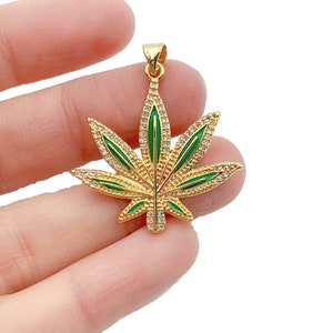 May include: Gold-tone pendant featuring a green marijuana leaf design with clear rhinestones.
