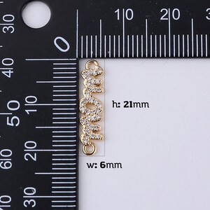 May include: Gold charm with the word "mom" spelled out in rhinestones. The charm is 21 mm high and 6 mm wide.