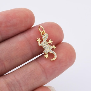 Op de afbeelding: Gouden hanger met een gedetailleerd gecko-ontwerp met heldere, glinsterende strasssteentjes.