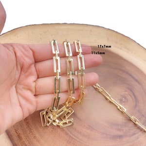 Puede incluir: Tres cadenas de oro con eslabones rectangulares. Las cadenas están dispuestas sobre una superficie de madera. Los eslabones de la cadena superior miden 17 mm x 7 mm, y los eslabones de la cadena inferior miden 11 mm x 5 mm.