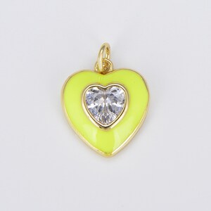 May include: A gold heart-shaped pendant with a clear rhinestone in the center. The pendant is yellow and has a shiny finish.