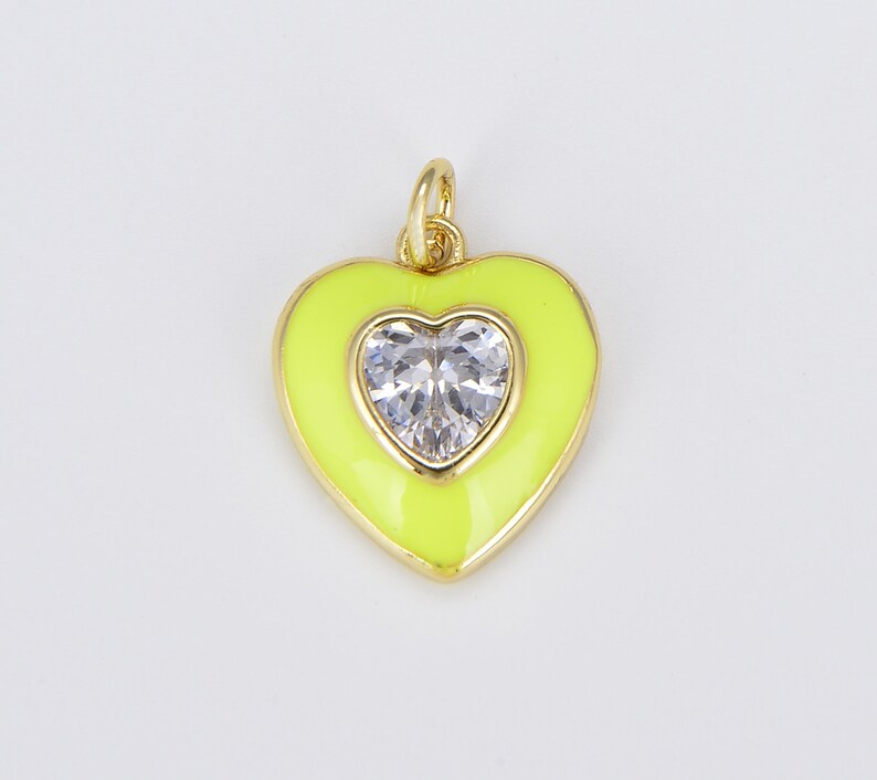 May include: A gold heart-shaped pendant with a clear rhinestone in the center. The pendant is yellow and has a shiny finish.