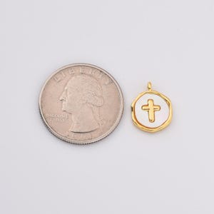 May include: Gold-toned pendant charm with a white enamel cross design. The charm is about the size of a US quarter.