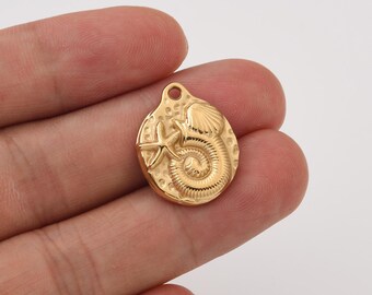 May include: A gold-colored pendant with a textured surface. The pendant features a starfish, a seashell, and a spiral design. It has a small hole at the top for attaching to a chain or other jewelry component.