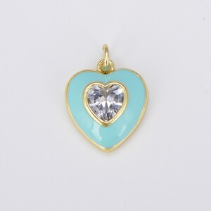 May include: A gold heart-shaped charm with a clear crystal in the center. The heart is outlined in gold and has a light blue enamel finish.