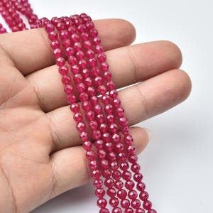 May include: Strands of faceted, deep red gemstone beads. The beads are small, round, and have a sparkling, polished finish. The beads are strung together, creating a flowing, textured appearance. The color is a rich, vibrant red.