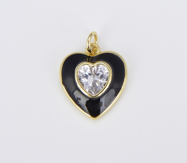 May include: Gold heart-shaped pendant with black enamel and a clear rhinestone in the center.