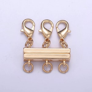 May include: Gold-toned metal clasp with three lobster claw clasps and three jump rings. The clasp has a rectangular shape with two sections.