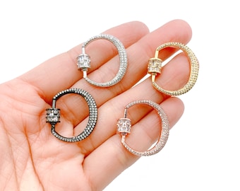 Könnte beinhalten: Vier unterschiedlich farbige Metallverschlüsse mit einem klaren Kristalldesign. Die Verschlüsse sind in Silber, Gold, Roségold und Schwarz.