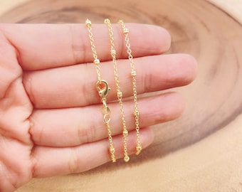 May include: A gold chain necklace with small round beads. The chain is delicate and has a simple design.
