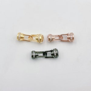 May include: Three metal clasps with a decorative row of clear rhinestones. The clasps are in gold, rose gold, and black.