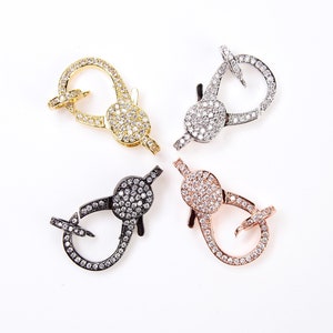 May include: Four lobster claw clasps with clear rhinestones. The clasps are in gold, silver, black, and rose gold.