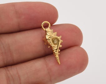 Op de afbeelding: Een goudkleurige schelpenhanger met een textuuroppervlak en een kleine lus aan de bovenkant om aan een ketting of koord te bevestigen. De hanger is een gedetailleerde miniatuurreplica van een schelp.