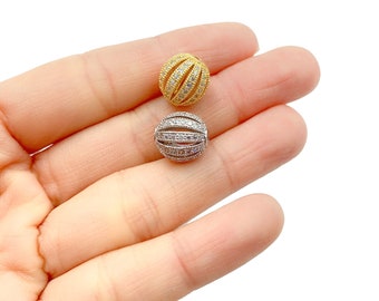 May include: Two round beads with a grooved design, one gold and one silver, both with clear crystal accents.