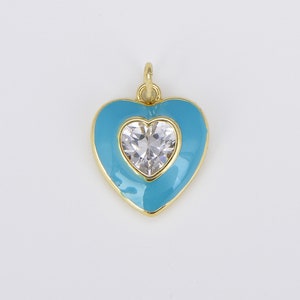 May include: A gold heart-shaped pendant with a clear crystal in the center. The heart is outlined in gold and filled with a light blue enamel.