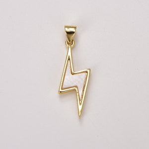 May include: A gold-tone pendant in the shape of a lightning bolt with a white mother-of-pearl inlay.