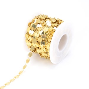 May include: A spool of gold-colored chain with round, flat links. The chain is wound around a white plastic spool.