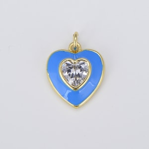May include: A gold heart-shaped pendant with a clear crystal in the center. The heart is outlined in gold and filled with a light blue enamel.