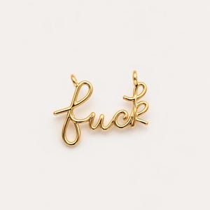 May include: A gold-colored pendant in the shape of the word "fuck" in cursive script. The pendant is made of wire and has loops at the top for hanging. The background is plain white.