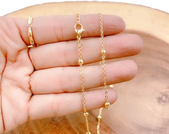 May include: A gold chain necklace with small round beads. The chain is delicate and has a simple design.