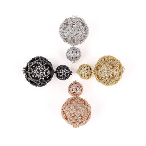 May include: Five decorative ball clasps with a cage design. The clasps are in silver, black, gold, and rose gold finishes. Each clasp has a smaller ball attached to it.