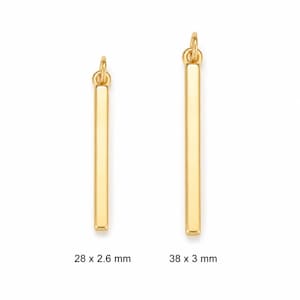 May include: Two gold-colored metal bar pendants with attached jump rings. The left pendant measures 28 x 2.6 mm, and the right pendant measures 38 x 3 mm. Both items feature a smooth, polished finish and a vertical rectangular shape.
