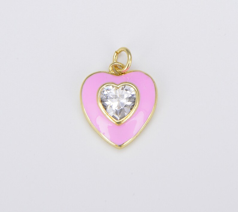 May include: A gold heart-shaped charm with pink enamel and a clear rhinestone in the center.