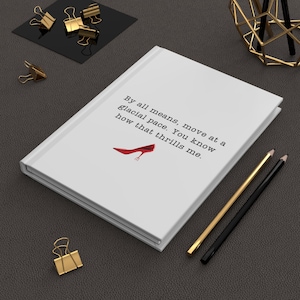 Könnte beinhalten: Ein weißes Notizbuch mit dem Text "By all means, move at a glacial pace. You know how that thrills me." und einer roten High-Heel-Illustration. Goldene und schwarze Bleistifte und Büroklammern sind ebenfalls vorhanden.