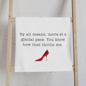 May include: White kitchen towel with black text that reads "By all means, move at a glacial pace. You know how that thrills me." A red high-heeled shoe with a pointed toe and a stiletto heel is printed below the text.