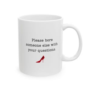 May include: White ceramic mug with a black text that reads "Please bore someone else with your questions." A red high-heeled shoe graphic is below the text. The mug has a curved handle.