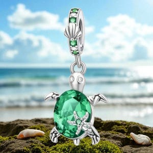 May include: A silver turtle charm featuring a large oval green crystal shell, a small silver starfish accent, and two clear stones for eyes. The bail is decorated with a silver seashell motif and alternating green and clear round stones.
