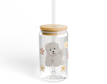 May include: A clear glass tumbler with a white dog and flowers printed on the side. The tumbler has a bamboo lid and a clear plastic straw.