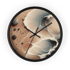 Puede incluir: Un reloj de pared redondo con marco negro y un diseño abstracto beige y gris. El diseño presenta líneas y formas que se arremolinan que se asemejan a olas rompiendo en una playa de arena. Hay pequeñas piedras negras esparcidas por la arena.