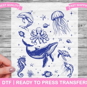 Op de afbeelding: Een digitaal ontwerp met een blauwe walvis, octopus, kwal, zeepaardje, schildpad en garnaal. Het ontwerp is perfect voor het maken van strijktransfers voor T-shirts, tassen en andere kleding.