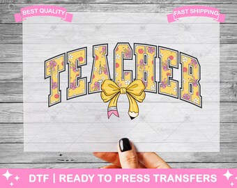 May include: A yellow and pink "Teacher" design with a bow and pencil. The letters are outlined in black and have a floral pattern inside. The design is on a white background.