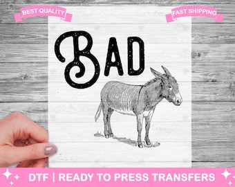 May include: Black and white illustration of a donkey with the word "BAD" in a stylized font above it. The image is on a white background.