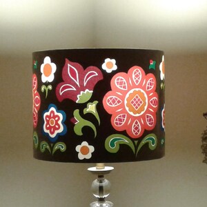 May include: A brown lampshade with a floral design featuring red, pink, white, and green flowers. The flowers are stylised and have a folk art feel.