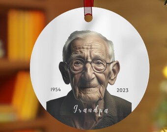 Może przedstawiać: Biała, okrągła ozdoba choinkowa z fotografią starszego mężczyzny w okularach. Ozdoba ma napis "1954" i "2023" po obu stronach zdjęcia oraz napis "Grandpa" pod zdjęciem.