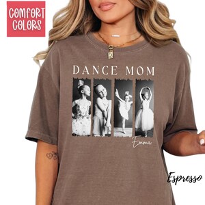 Peut inclure: T-shirt couleur expresso avec les mots "DANCE MOM" au-dessus de quatre images en noir et blanc de jeunes danseuses. Le nom "Emma" est &eacute;crit en dessous des images. Le t-shirt porte &eacute;galement les mots "COMFORT COLORS" dans un encadr&eacute; rouge.