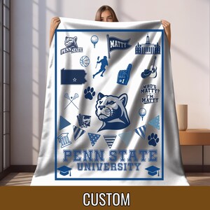 May include: A white fleece blanket featuring a blue border and various Penn State University themed graphics including a Nittany Lion mascot, a lacrosse player, a guitar, a graduation cap, and the text Penn State University and Who's Matty? I'm Matty.