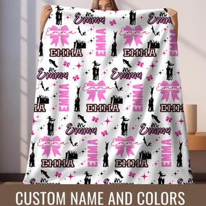 May include: White fleece blanket with a pink and black repeating pattern of cheerleaders, bows, stars, and the name "Emma".